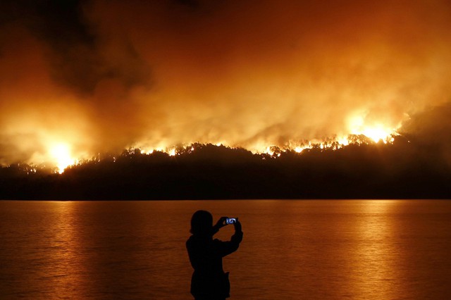 Người phụ nữ chụp ảnh đám cháy rừng tại vườn quốc gia Los Alerces ở vùng Patagonia, Argentina. Một tia sét được cho là nguyên nhân gây ra vụ hỏa hoạn.