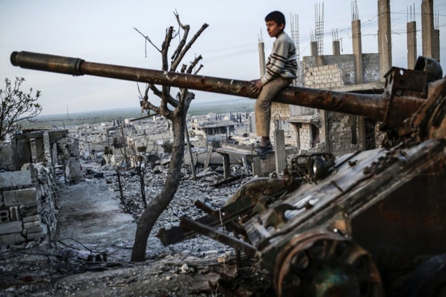 Cậu bé người Kurd ngồi trên xe tăng bị phá hủy tại thị trấn Kobani, Syria.