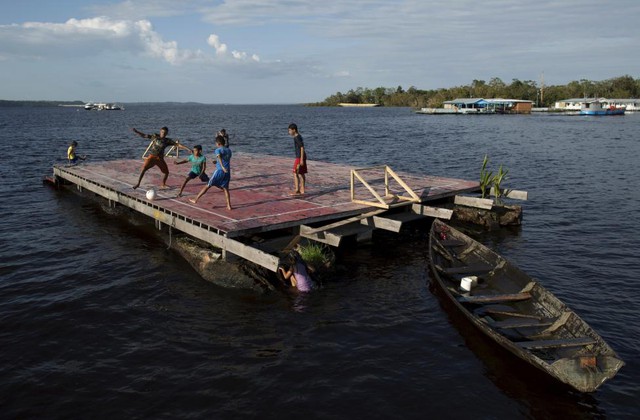 Các cậu bé chơi bóng đá trên một tấm gỗ trôi dạt gần bờ sông Rio Negro ở bang Amazonas, Brazil.