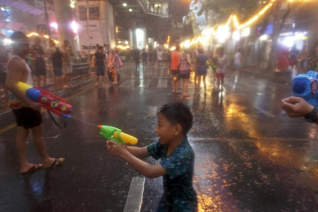 Một cậu bé dùng súng phun nước vào người đi đường trong lễ hội té nước Songkran ở Bangkok, Thái Lan.