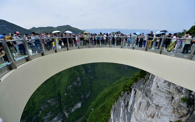Du khách ngắm phong cảnh từ trên cây cầu hình móng ngựa bằng kính trong suốt trong vườn quốc gia Long Cương ở Trùng Khánh, Trung Quốc.