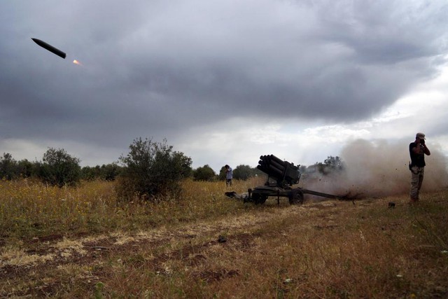 Chiến binh phiến quân Syria lấy tay bịt tai sau khi phóng rocket nhằm vào quân đội chính phủ ở khu vực ngoại ô Deraa.