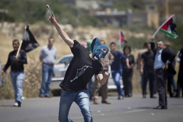 Nam thanh niên người Palestine ném đá vào binh sĩ Israel trong cuộc biểu tình tại cửa khẩu Hawara ở thành phố Nablus, Bờ Tây.