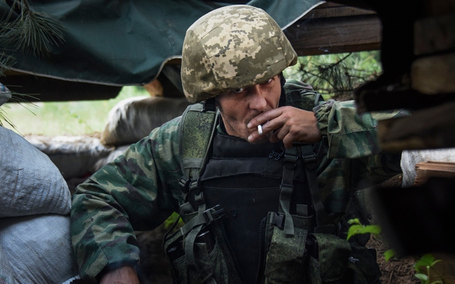 Một tay súng ly khai thân Nga hút thuốc dưới đường hào ở ngoại ô thành phố Donetsk, miền đông Ukraine.