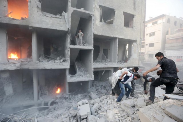 Những người đàn ông tìm kiếm nạn nhân sống sót trong đống đổ nát sau một trận pháo kích của quân đội chính phủ nhằm vào thành phố Damascus, Syria.