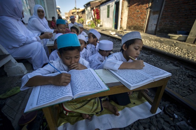 Trẻ em học cách đọc kinh Koran bên cạnh đường ray tàu hỏa ở Surabaya, Indonesia.