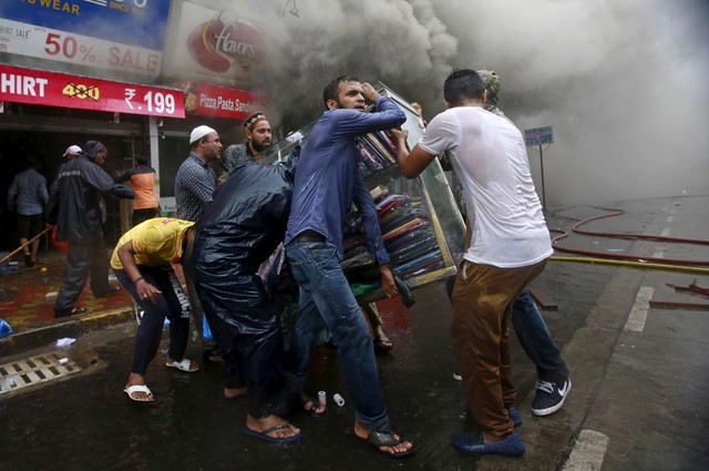 Mọi người sơ tán hàng hóa khỏi trung tâm thương mại bị hỏa hoạn ở thành phố Mumbai, Ấn Độ.