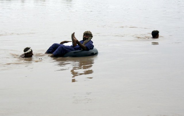 Nông dân giúp một người đàn ông vượt qua sông Chenab ngập lụt ở Faisalabad, Pakistan.