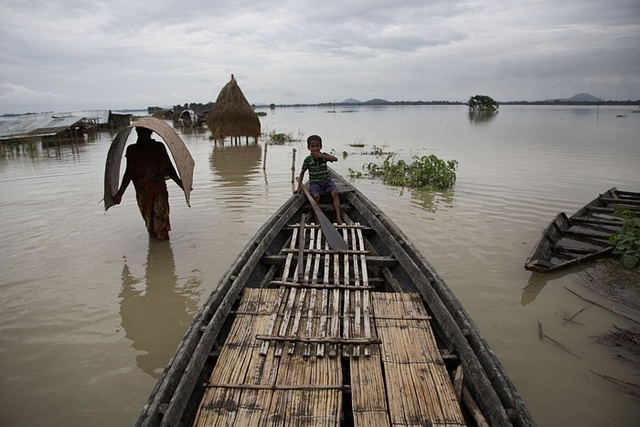Người dân di qua nước lũ gần ngôi làng Morisuti ở bang Assam, Ấn Độ.