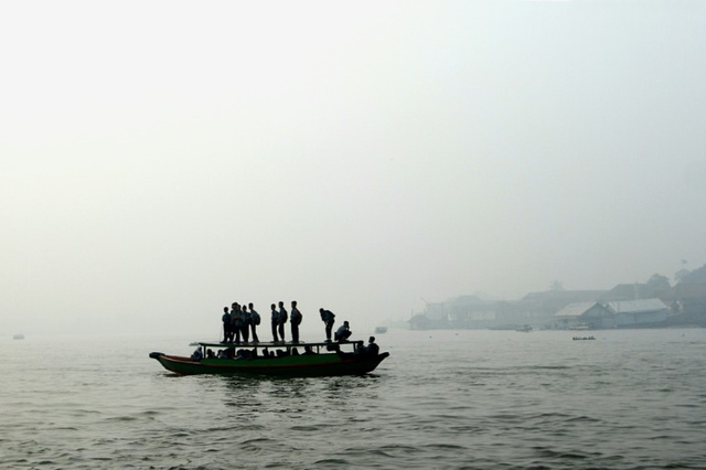 Học sinh Indonesia qua sông bằng thuyền trong màn khói mù dày đặc gây ra bởi các đám cháy rừng ở Palembang trên đảo Sumatra.
