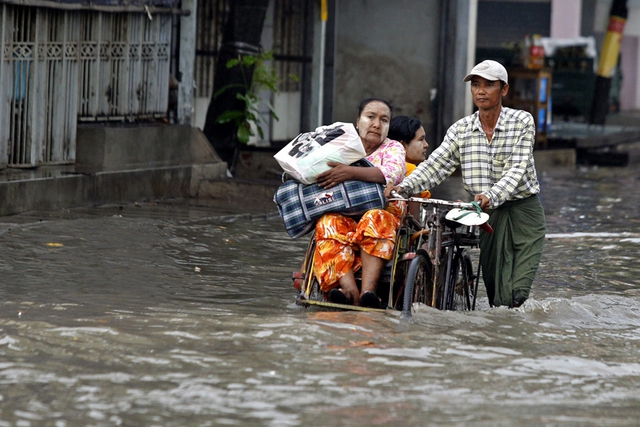 Người đàn ông đẩy xe ba bánh chở khách qua đường phố ngập lụt ở Mandalay, Myanmar.