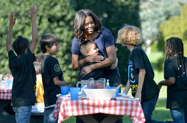 Đệ nhất phu nhân Tổng thống Mỹ Michelle Obama ôm một cậu bé, trong khi thu hoạch rau tại Nhà Trắng cùng các em học sinh của một trường tiểu học.