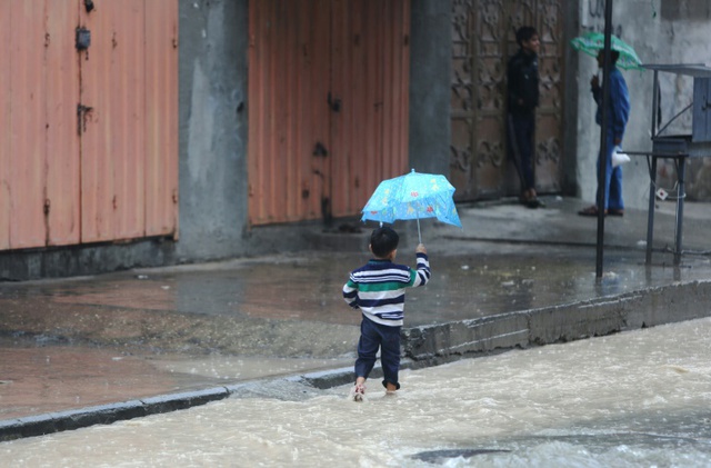 Cậu bé người Palestine cầm ô đi trên đường ngập nước ở thành phố Gaza.