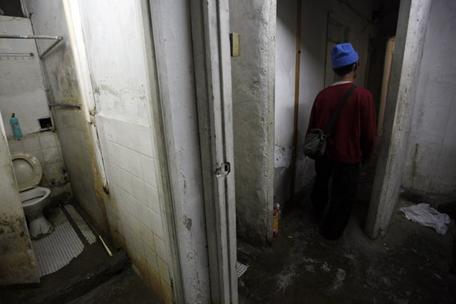 
Ông Ng, 60 tuổi, đang đi ra từ một nhà vệ sinh công cộng gần căn hộ 5,5​m2 của mình trong một tòa nhà ở Hong Kong. Ông Ng phải trả số tiền thuê nhà hàng tháng là 1.250 ​dollar Hong Kong (161 ​USD). Loại nhà cho thuê kiểu này thường là bất hợp pháp và có thể dẫn tới các vấn đề về an toàn và vệ sinh nếu không được xử lý đúng cách. (Nguồn: Reuters)
