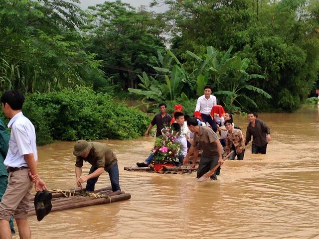 
Gia đình nhà trai dùng bè để vượt qua đoạn nước ngập đi ăn hỏi.
