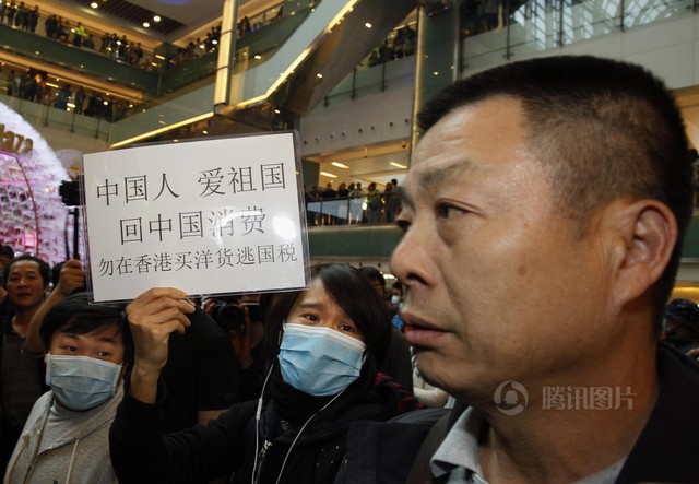 Một người Hồng Kông giơ tấm biển Người Trung Quốc đại lục yêu nước thì hãy về đại lục mua sắm, đừng mua hàng hiệu ở Hồng Kông để trốn thuế. Ảnh: QQ.