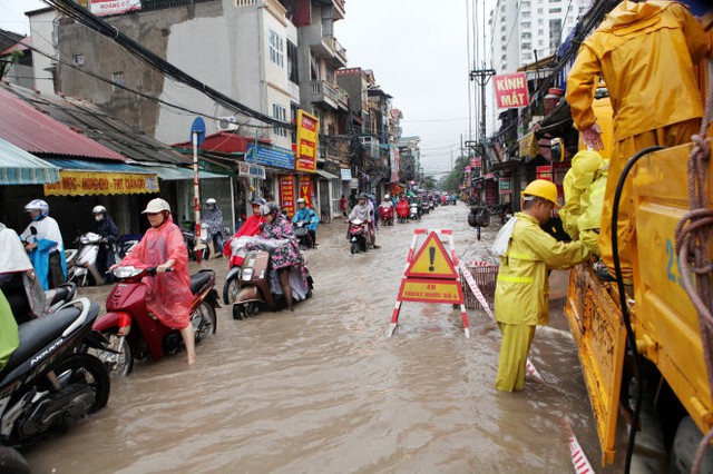 Nhân viên Công ty thoát nước Hà Nội phải huy động xe chuyên dụng và máy bơm để bơm nước từ phố Định Công ra cống bên đường Giải Phóng - Ảnh: T.Phùng/Tuổi trẻ