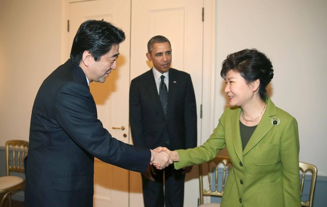 Tổng thống Hàn Quốc Park Geun-hye (phải) bắt tay Thủ tướng Nhật Shinzo Abe trước sự chứng kiến của Tổng thống Mỹ Barack Obama, trước cuộc họp giữa 3 nhà lãnh đạo tại The Hague, Hà Lan hôm 25/3. Ảnh: AP.