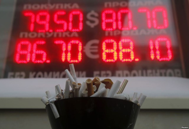 
Chiếc gạt tàn với đầy đầu lọc thuốc lá trước một bảng điện tử thông báo tỷ giá giữa đồng USD và đồng ruble ở Moscow, Nga.
