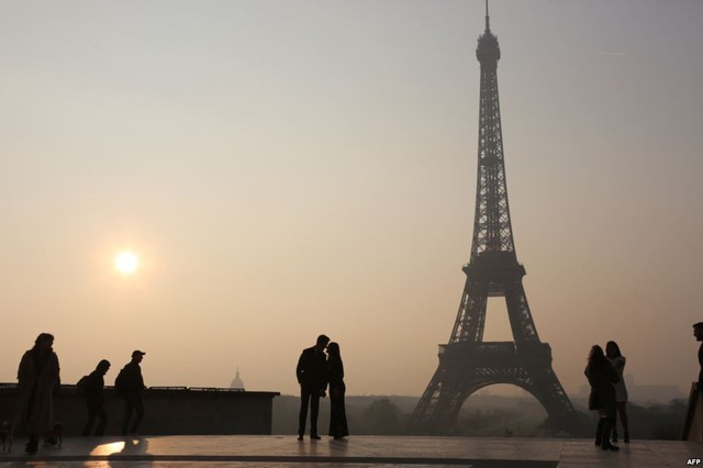 Cặp đôi tình tứ với nhau lúc bình minh trước tháp Eiffel ở thành phố Paris, Pháp.