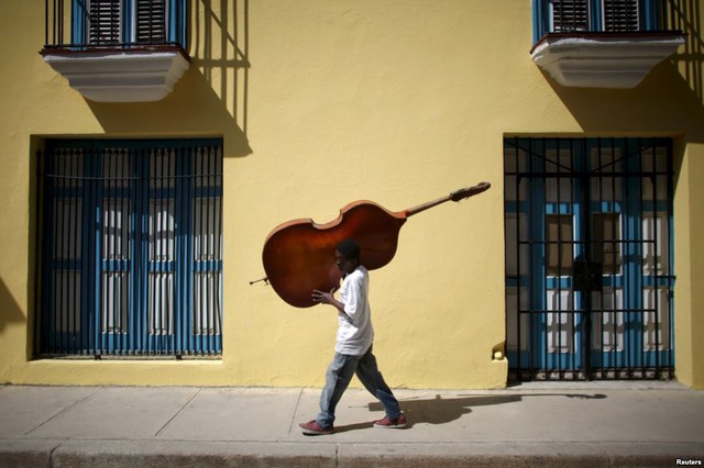 Nghệ sĩ vác cây đàn cello đi trên đường phố ở Havana, Cuba.