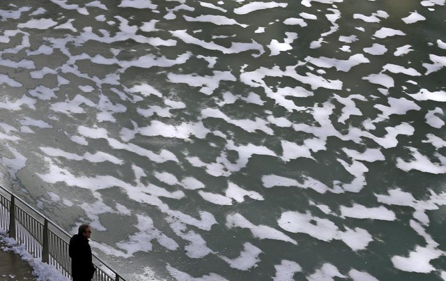 Người đàn ông nhìn mặt nước trên sông đóng băng tại thành phố Chicago, bang Illinois, Mỹ.