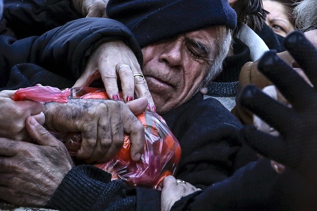 Người đàn ông ôm túi quýt khi mọi người nhận thực phẩm miễn phí do chính phủ phân phát tại thành phố Athens, Hi Lạp.