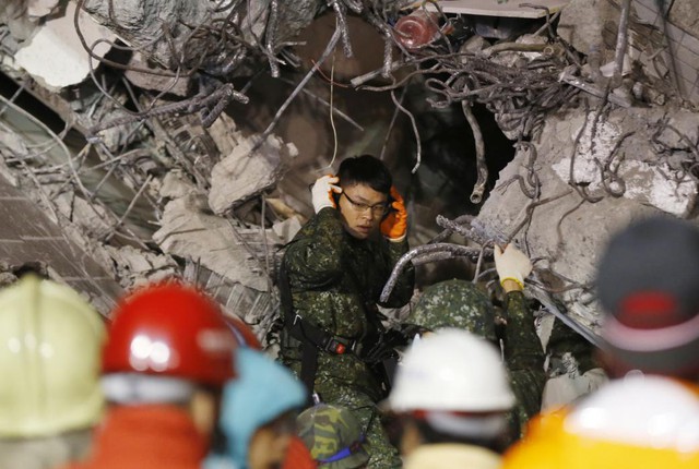 Binh sĩ cố gắng lắng nghe tiếng động từ nạn nhân sống sót mắc kẹt trong tòa nhà bị sập sau động đất ở Đài Nam, Đài Loan.