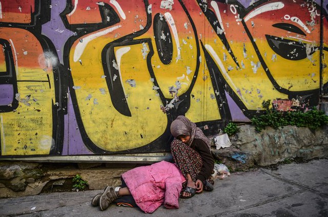 Cô gái người Syria ngồi ăn xin cạnh em bé đang nằm ngủ trên đường phố ở Istanbul, Thổ Nhĩ Kỳ.
