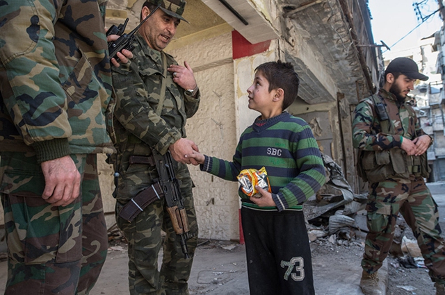 
Một cậu bé trò chuyện với các binh sĩ thuộc quân đội Arab Syria.
