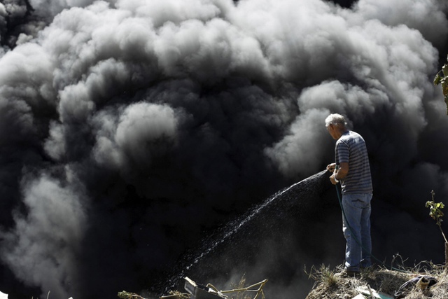 Người đàn ông cố gắng dập tắt cháy tại một bãi rác bất hợp pháp tại một khu ổ chuột ở San Jose, Costa Rica.