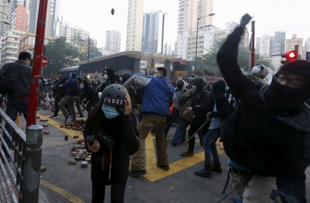 Nhà báo chạy tìm nơi ẩn ẩn nấp khi người biểu tình ném gạch vào cảnh sát chống bạo động tại khu phố Mongkok, Hong Kong.