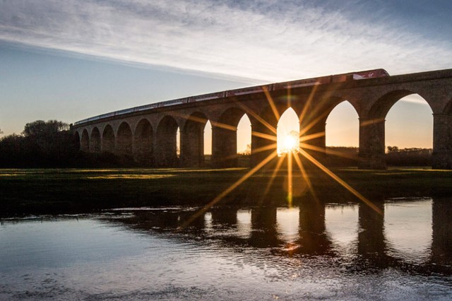 Tàu hỏa di chuyển qua cây cầu Arthington Viaduct lúc bình minh ở Yorkshire, Anh.