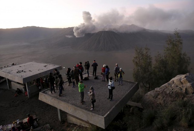 Du khách ngắm cảnh bình minh gần núi lửa Bromo đang phun trào tro bụi ở Probolinggo, Indonesia.
