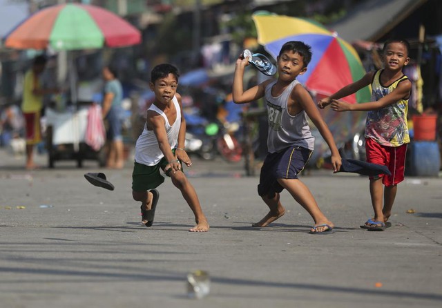 Trẻ em thích thú với trò chơi dùng dép ném vỏ hộp trên đường phố ở Navotas, Philippines.
