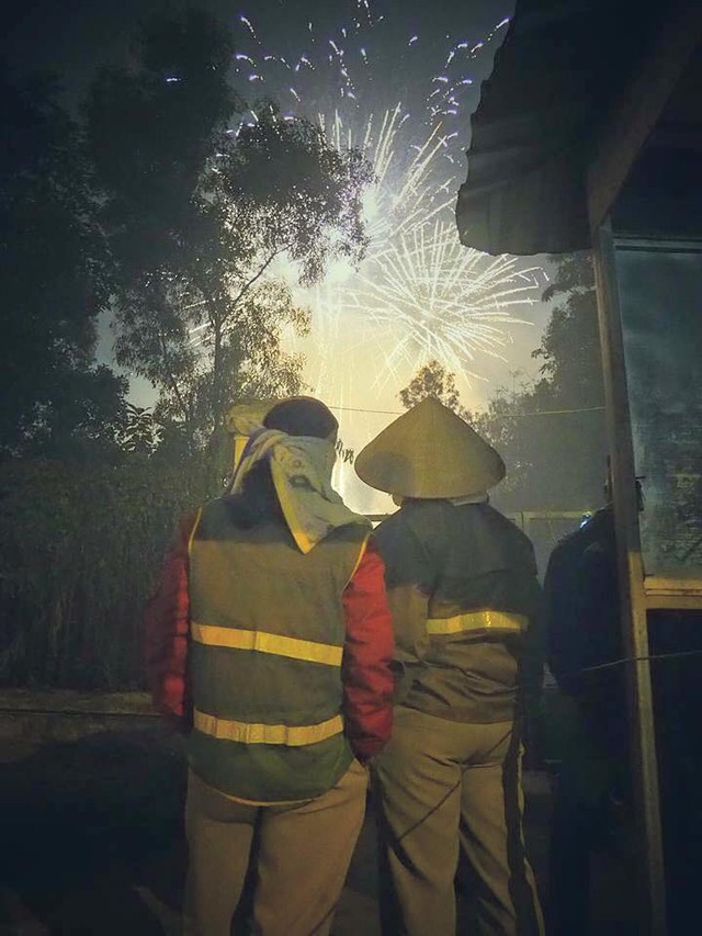 
2 người công nhân vệ sinh môi trường đứng lặng lẽ ngắm pháo hoa gây xúc động. Hẳn họ đang mong từng phút để được trở về bên người thân đón Tết. (Nguồn ảnh: Thang Nguyen Manh)
