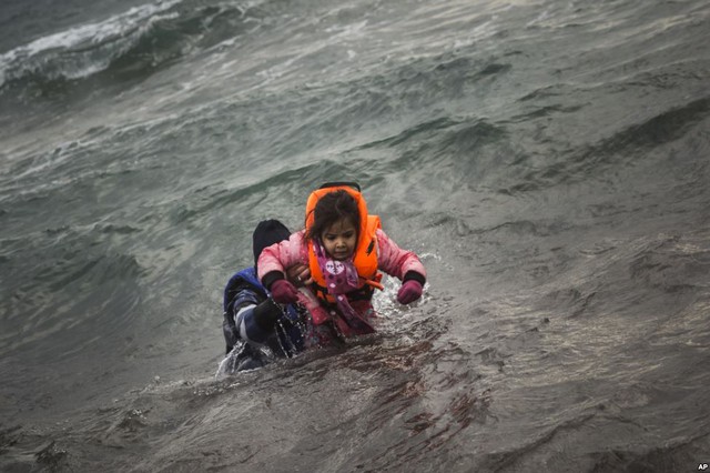 Người đàn ông di cư bế con gái nhỏ vào bờ sau khi họ bị ngã từ thuyền xuống biển gần đảo Lesbos, Hi Lạp.