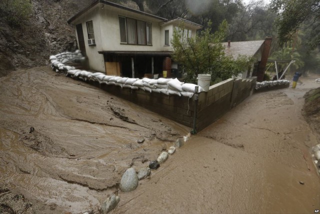 Bùn đất chảy theo nước lũ từ trên núi phủ quanh một ngôi nhà ở thành phố Monrovia, bang California, Mỹ.