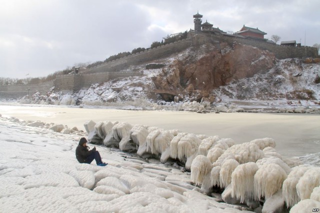 Người đàn ông chụp ảnh băng tuyết bao phủ các khối đá dọc bờ biển ở thành phố Bồng Lai, Trung Quốc.