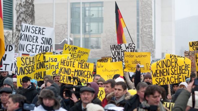 Hàng trăm người Nga tổ chức biểu tình bên ngoài dinh Thủ tướng Đức Angela Merkel tại thủ đô Berlin cuối tuần qua. Trong số những tấm biểu ngữ phản đối, có tấm viết: Con cái chúng tôi đang gặp nguy hiểm. Ảnh BBC.