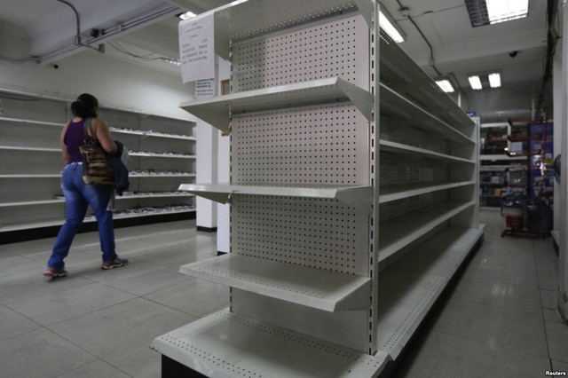 Người phụ nữ đi qua những kệ trống rỗng trong một hiệu thuốc ở thành phố Caracas, Venezuela.