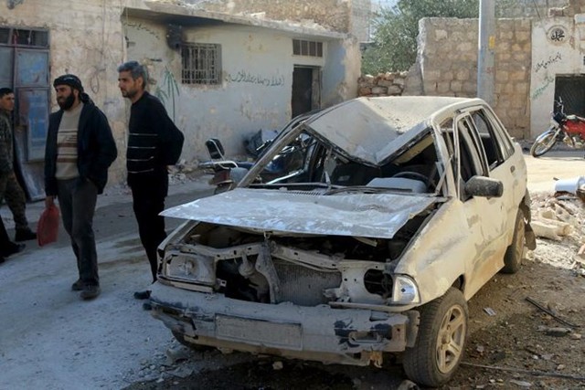 Người dân đứng gần một chiếc xe ôtô bị phá hoại tại thị trấn Darat Izza, tỉnh Aleppo (Syria).