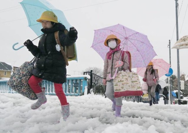 Học sinh Tokyo đi học trong tuyết giá sáng 18-1 - Ảnh: Reuters