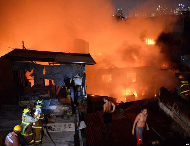 Lính cứu hỏa và người dân cố gắng dập tắt đám cháy bùng phát tại một khu ổ chuột ở thành phố Manila, Philippines.