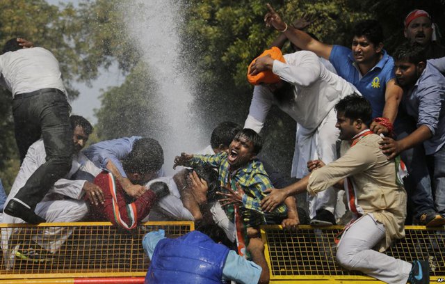 Cảnh sát dùng vòi rồng phun nước để giải tán người biểu tình trước tòa nhà quốc hội ở New Delhi, Ấn Độ.