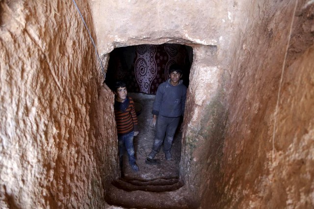 Các cậu bé đứng dưới hầm được đào trong lòng núi.