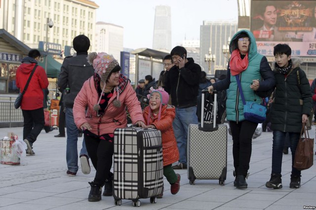 
Bé gái giúp gia đình đẩy hành lý tại nhà ga tàu hỏa ở Bắc Kinh, Trung Quốc, để bắt tàu về quê nghỉ Tết.
