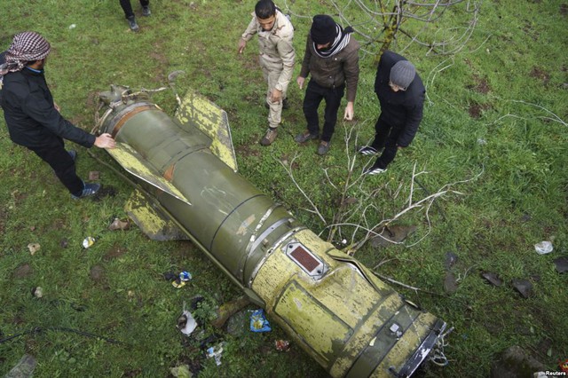 Các chiến binh quân nổi dậy kiểm tra một mảnh tên lửa rơi xuống khu vực ngoại ô thành phố Quneitra, Syria.