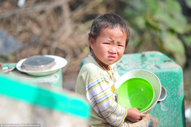 
Một đứa trẻ thơ thẩn ngồi một mình ở bãi rác. Ảnh: Daily Mail

