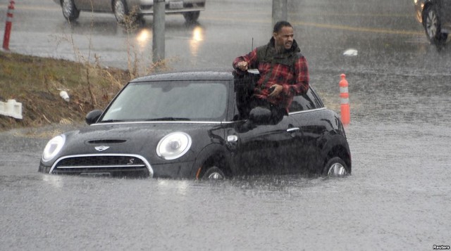 Người đàn ông trèo ra khỏi chiếc ô tô bị ngập trong nước lũ ở thị trấn Van Nuys, bang California, Mỹ.